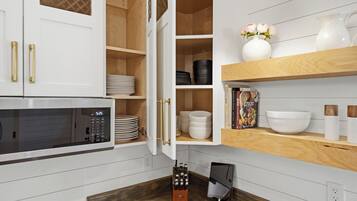 A kitchen with white cabinetry, a microwave, and various kitchenware.