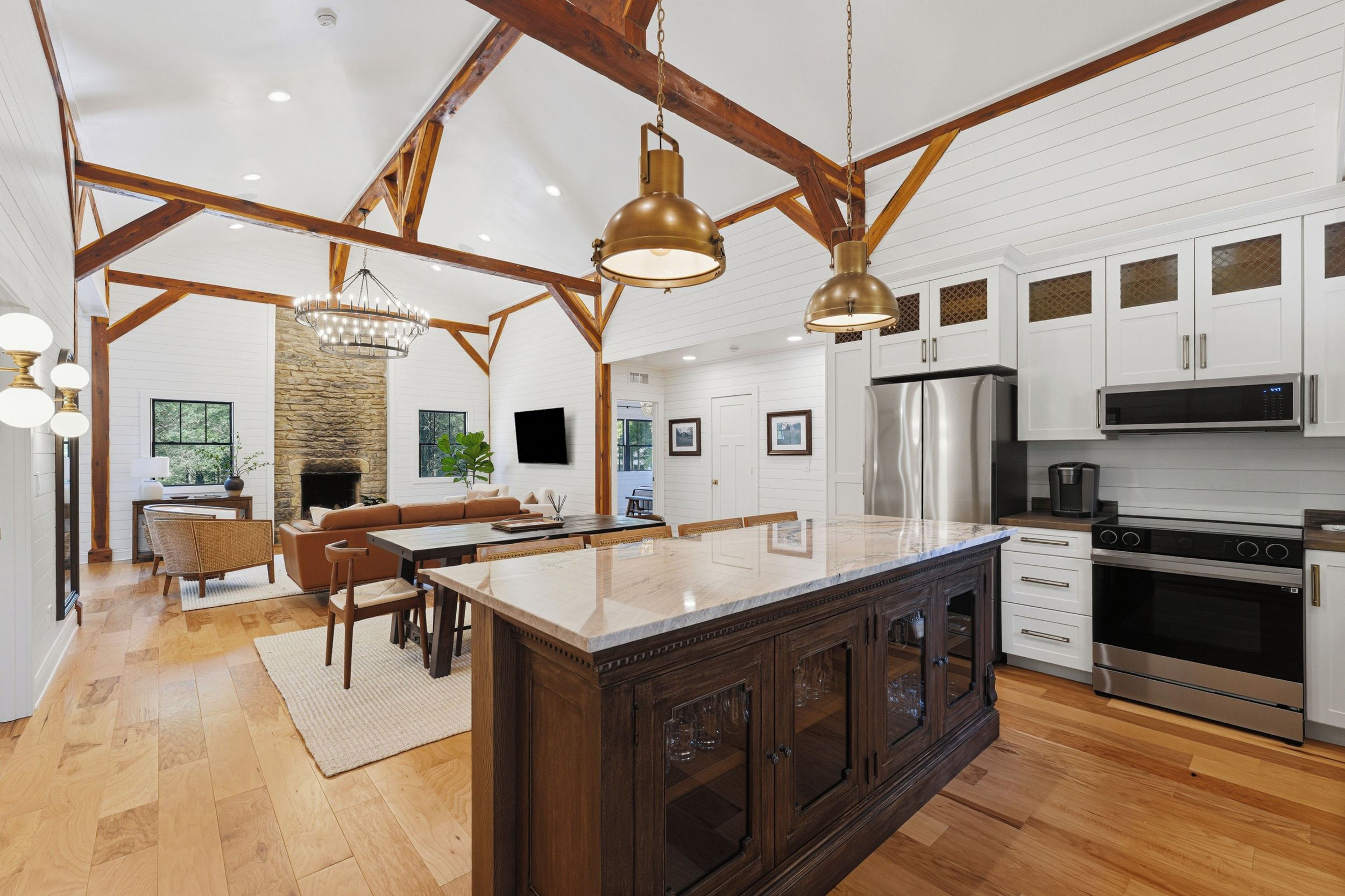 A spacious kitchen with a large island, wooden beams, and modern appliances.