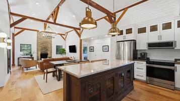 A spacious kitchen with a large island, wooden beams, and modern appliances.