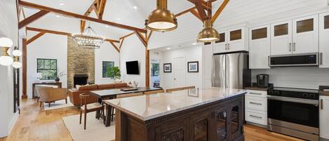A spacious kitchen with a large island, wooden beams, and modern appliances.
