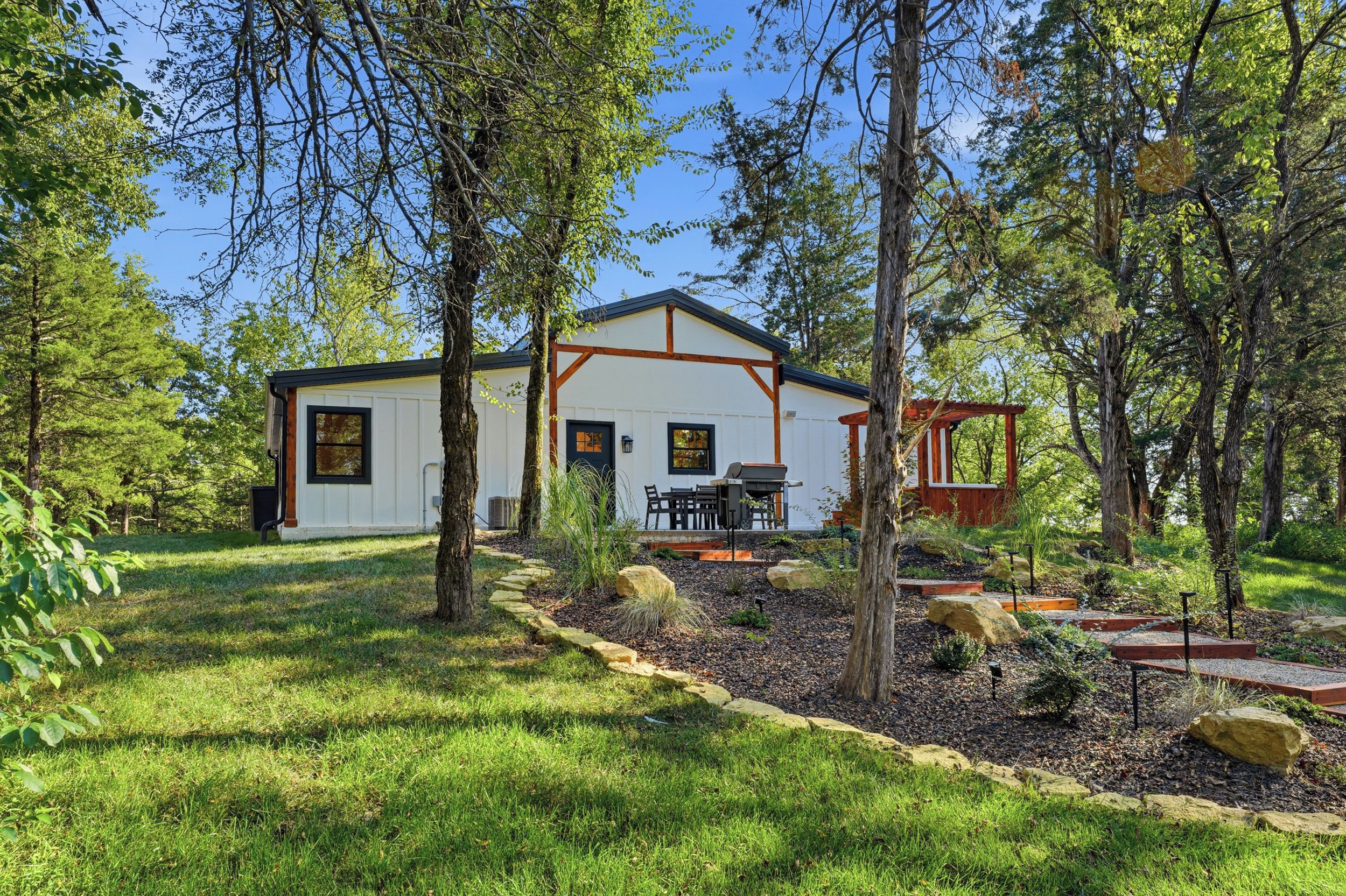 A modern house with a patio, surrounded by a well-maintained garden and trees.