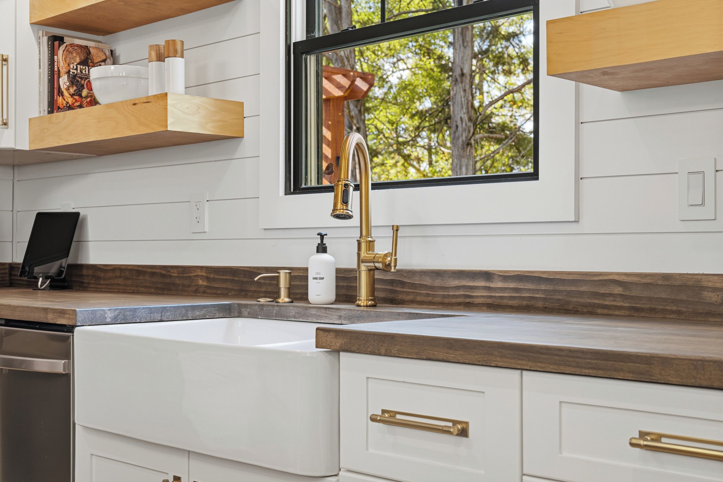 Una cocina con un lavamanos blanco, grifo dorado y encimera de madera.