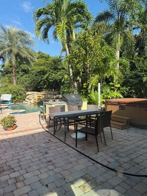 En patio med pool, jacuzzi og et bord med stole.