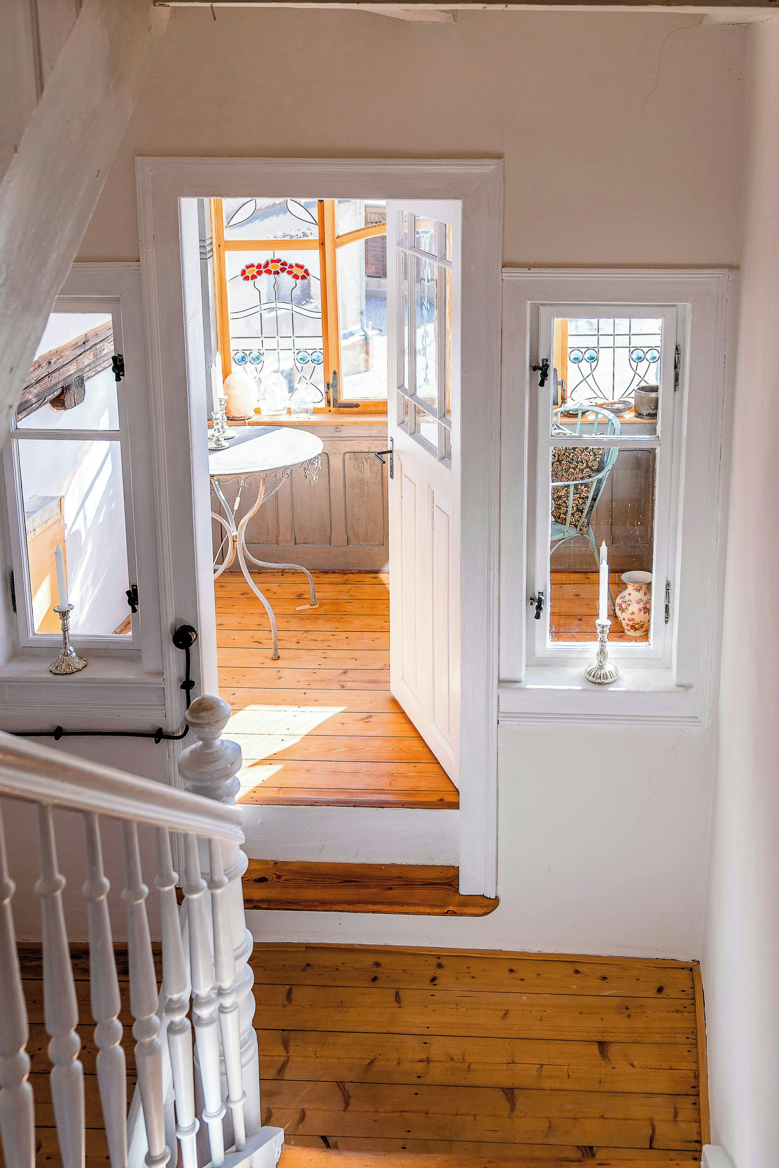 Een trap die leidt naar een kamer met een houten vloer en een witte balustrade.