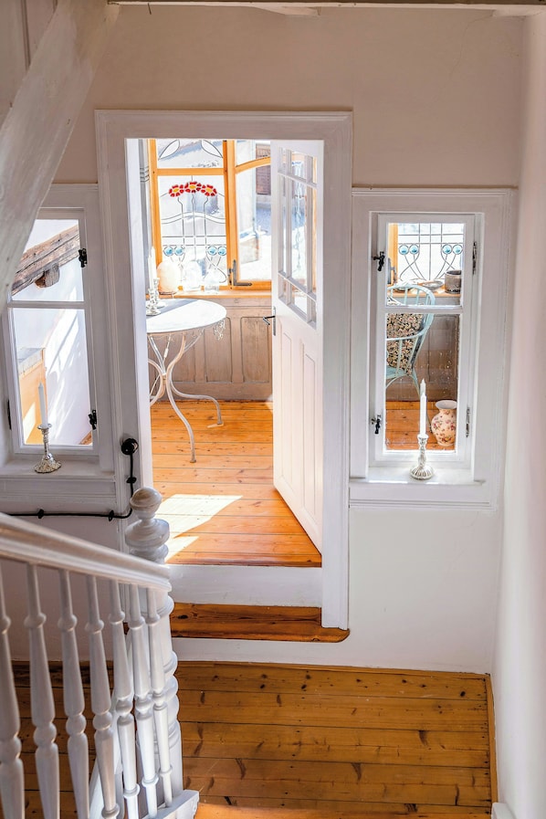 A staircase leading to a room with a wooden floor and a white railing.