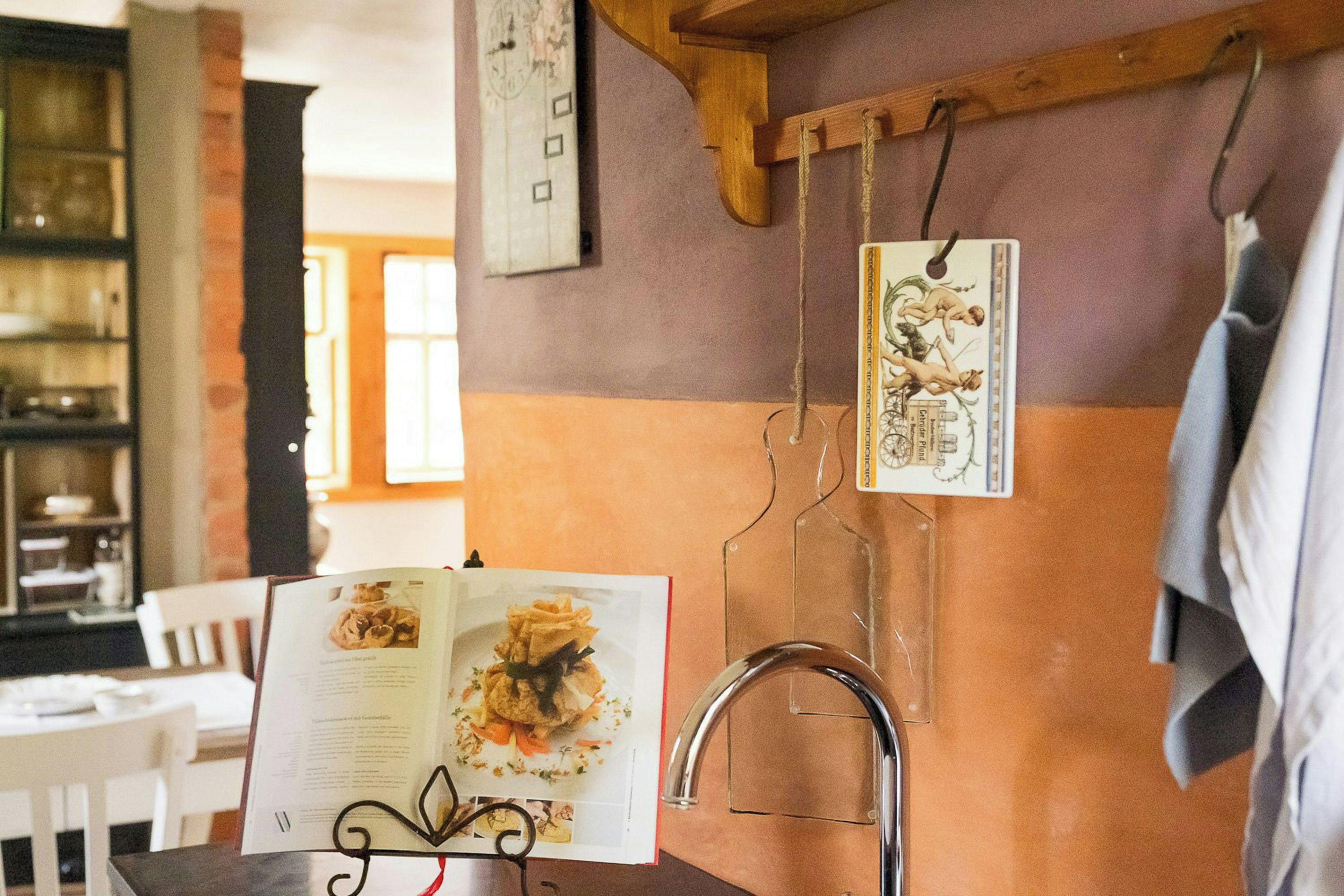 Een keuken met een ophangbaar menu, een boek en een metalen kraan.