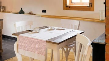 Un comedor con una mesa de madera, sillas blancas y una lámpara colgante.