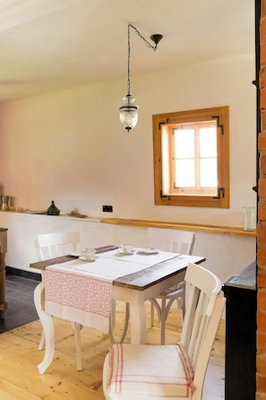 A dining area with a wooden table, white chairs, and a hanging light fixture.