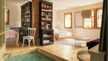 Un dormitorio con una cama, una estantería, una silla, una mesita y una ventana.