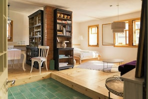 A bedroom with a bed, a bookshelf, a chair, a small table, and a window.