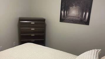 A bedroom with a bed, a dresser, and a wall-mounted picture.