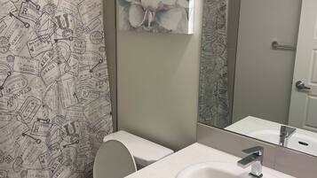Een badkamer met toilet, wastafel en douchegordijn versierd met reispostzegels.