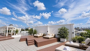 Terraza en la azotea con mobiliario exterior, sillones de sol y plantas en macetas.