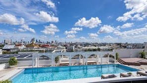 Una piscina en la azotea con el horizonte de la ciudad al fondo.