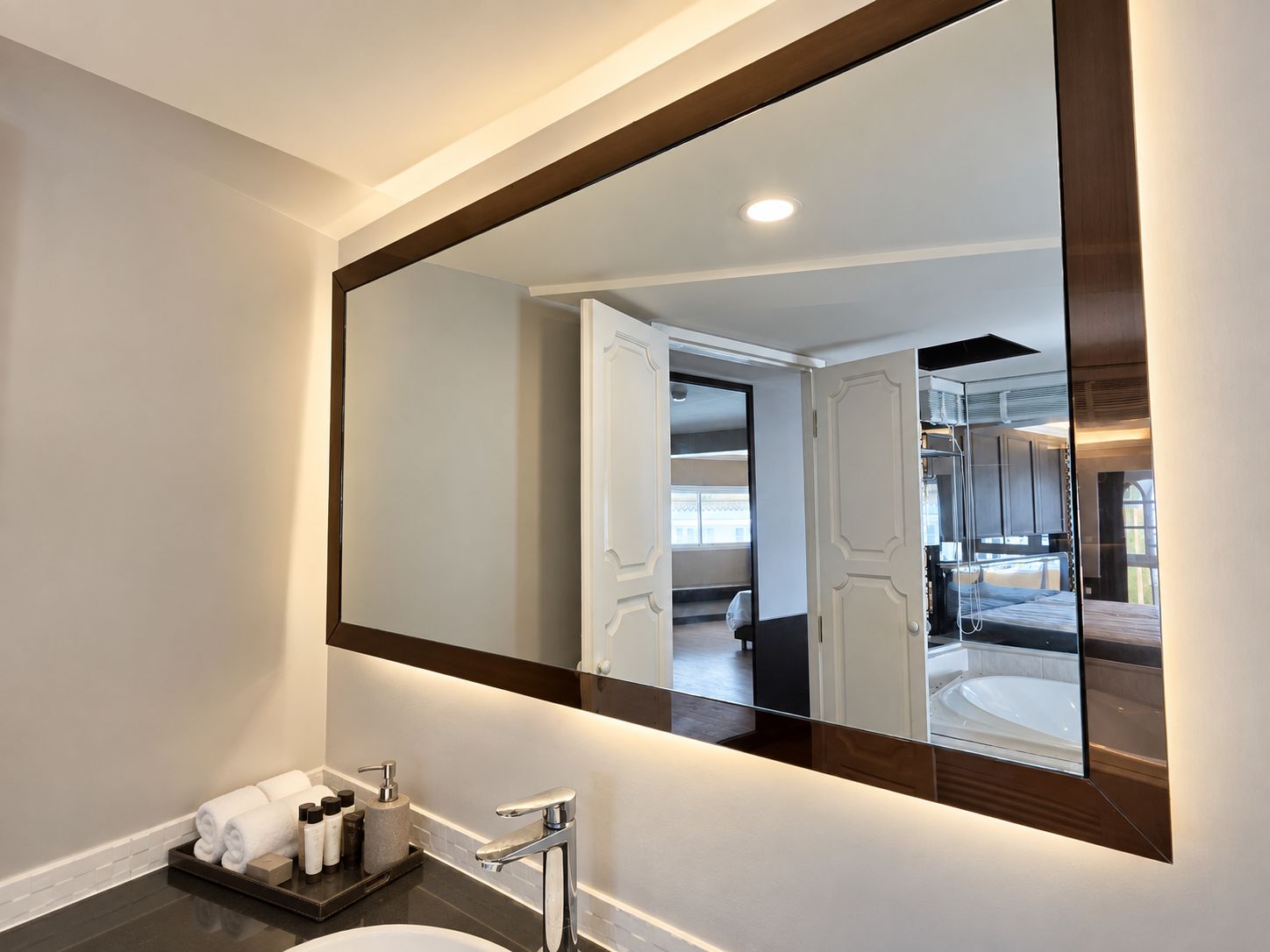 A modern bathroom with a large mirror, a sink, and a towel rack.