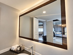 Un baño moderno con un espejo grande, un lavamanos y un perchero para toallas.