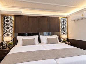 Habitación de hotel con cama doble, dos mesitas de noche, aire acondicionado de pared y paneles decorativos.
