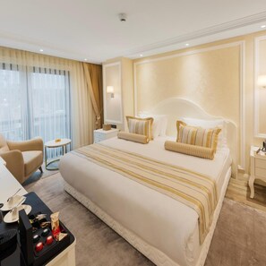 A hotel room with a large bed, a desk with a coffee maker, and a view of the city through the window. - Manning Residence (Istanbul)