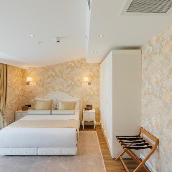 Un dormitorio con cama, mesitas de noche, un sillón y un armario.