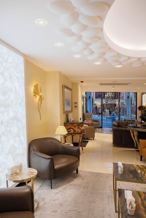 Un hall de hotel con diseño moderno, con sofás de cuero, una mesa de centro de mármol y una araña.