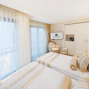 Una habitación de hotel con dos camas, televisión, una silla, una mesita y un armario.
