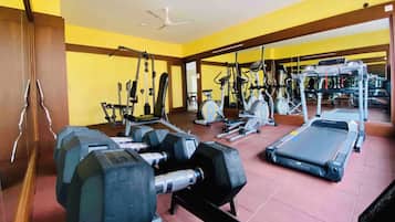 Un gimnasio con varios equipos de ejercicio, incluyendo mancuernas, una cinta de correr y máquinas de pesas.