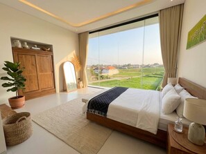 Ein Schlafzimmer mit großem Fenster, einem Bett, einem Holzschrank und einem Blumentopf.