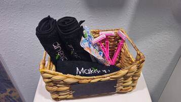 A wicker basket containing rolled black socks, a black towel, and pink hairbrushes.