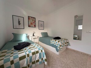 A bedroom with two beds, a bedside table with a lamp, and a mirror on the wall. - LOS JUNCOS I APARTMENT (401) (San Bartolomé de Tirajana)