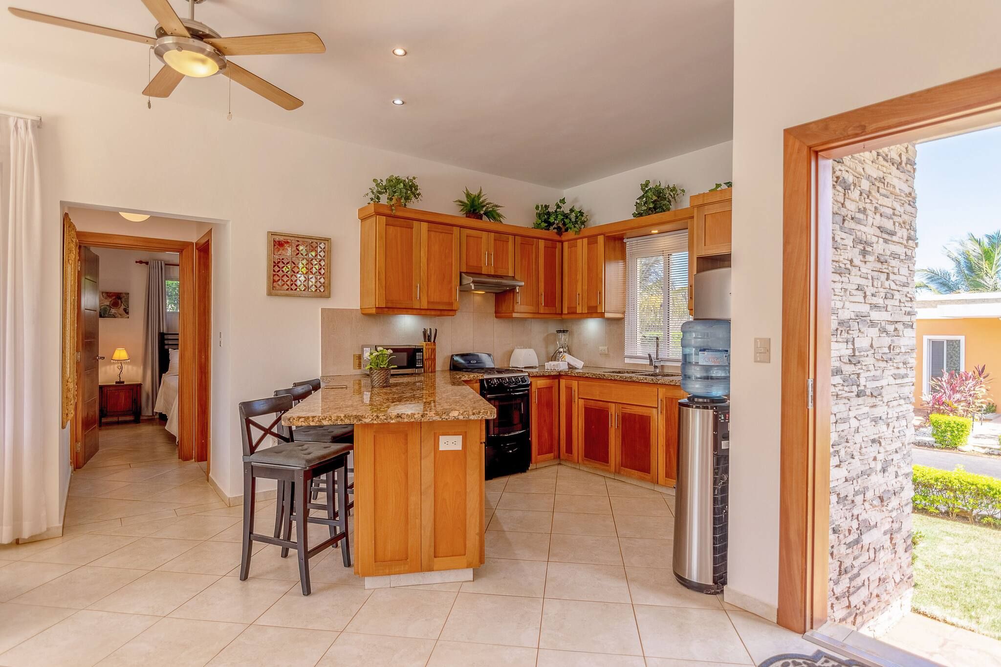A modern kitchen with wooden cabinets, a granite countertop, and a built-in island with bar stools.