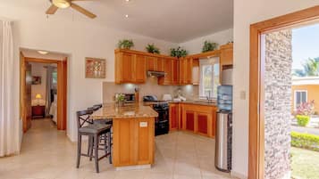 A modern kitchen with wooden cabinets, a granite countertop, and a built-in island with bar stools.