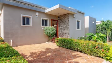A modern two-story house with a stone facade, a red door, and a paved driveway leading to the entrance.