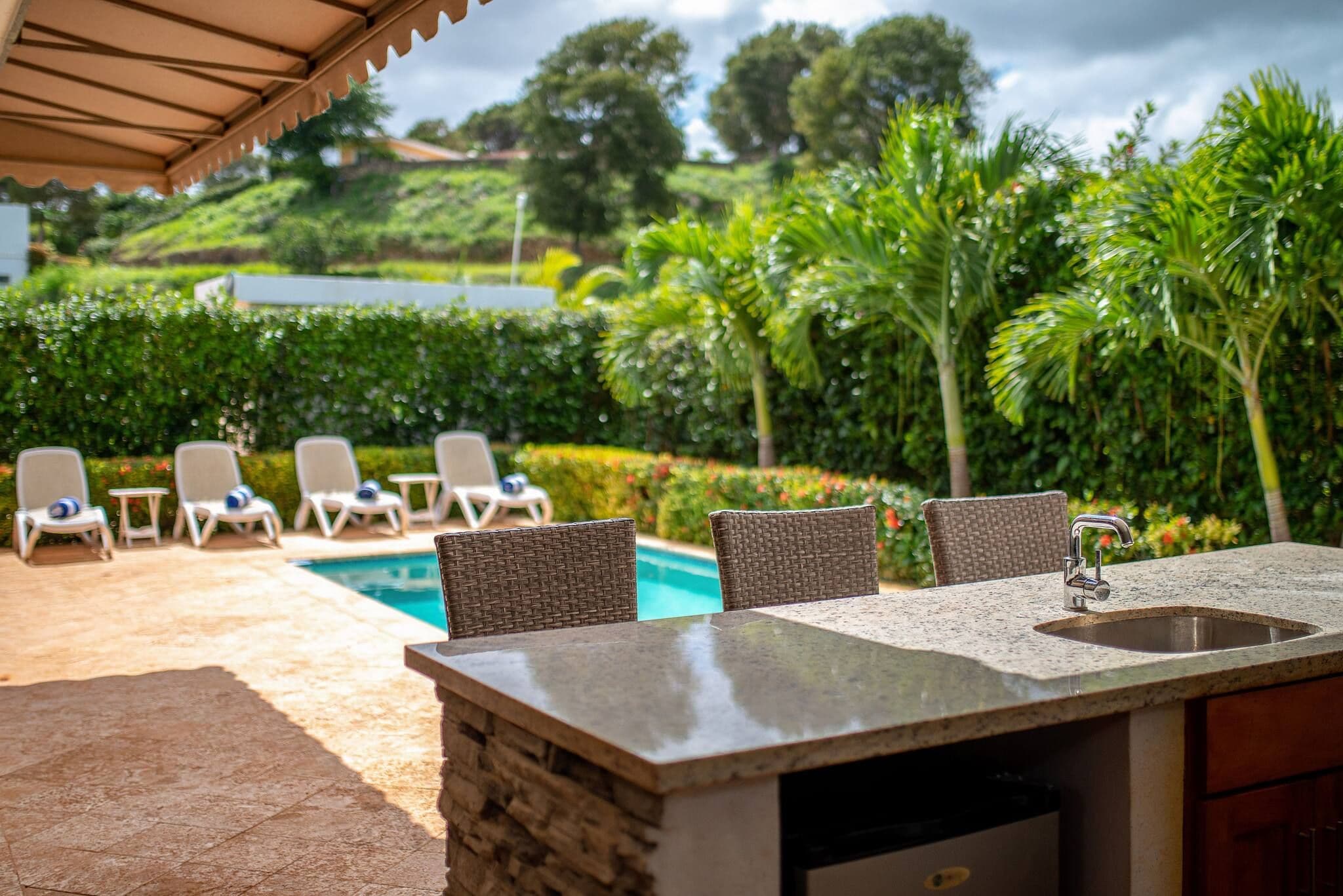 An outdoor pool area with lounge chairs and a stone bar.
