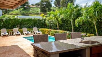An outdoor pool area with lounge chairs and a stone bar.