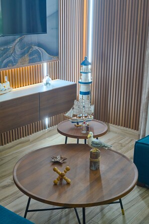 A modern living room with two round wooden tables, a decorative lighthouse, and a ship model. - Luxury Gateway 2BR Bayahibe Pool Beach (Bayahíbe La Romana)