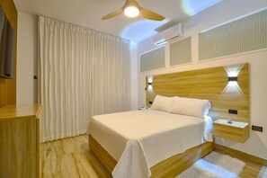 A modern bedroom with a wooden headboard, a bed with white bedding, a ceiling fan, and an air conditioning unit. - Luxury Gateway 2BR Bayahibe Pool Beach (Bayahíbe La Romana)