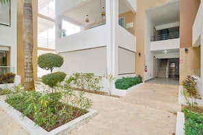 A multi-level indoor space with a central staircase, surrounded by greenery and a fire extinguisher. - Luxury Gateway 2BR Bayahibe Pool Beach (Bayahíbe La Romana)