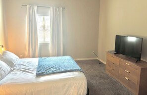 A bedroom with a bed, a television on a wooden dresser, and a window with curtains. - Enjoyable 3-bedroom Pool house in vibrant El Paso steps away from sports complex (El Paso)
