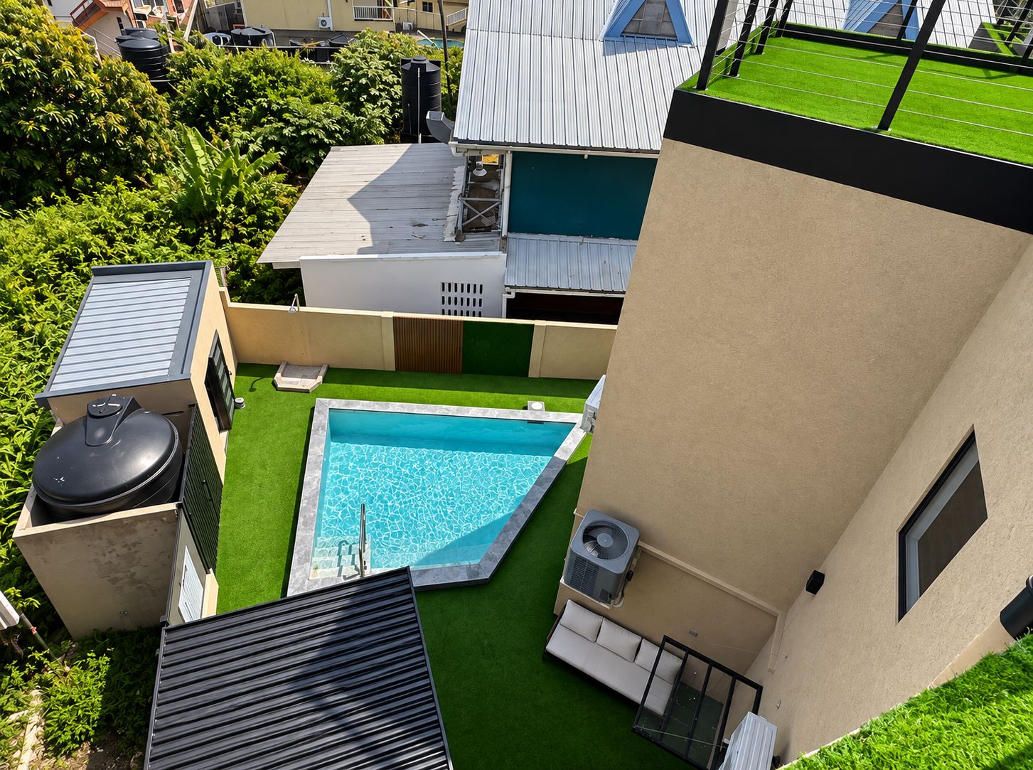 A rooftop pool area with a small pool, a barbecue grill, and a fan.