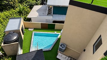 A rooftop pool area with a small pool, a barbecue grill, and a fan.