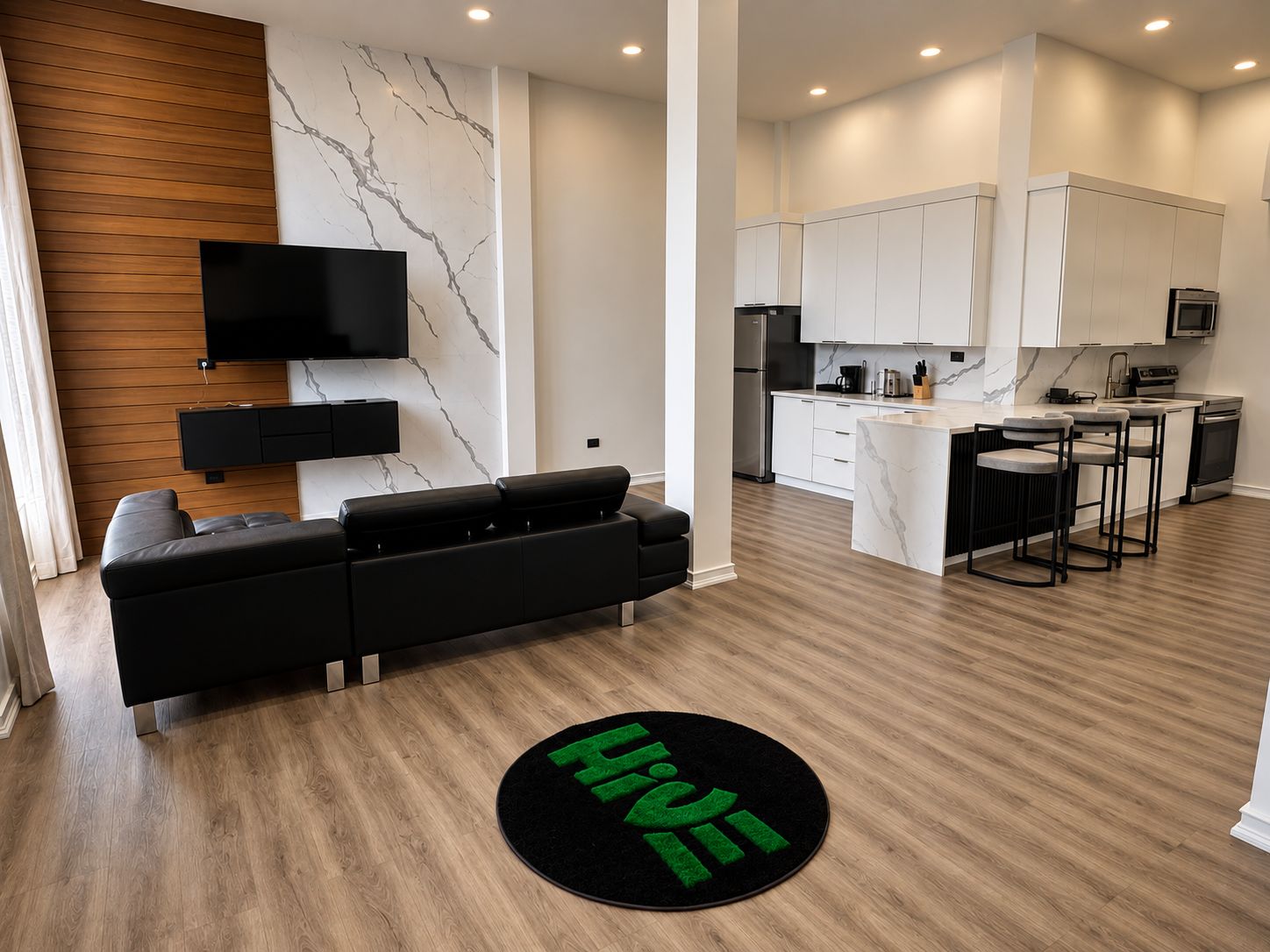 Una sala de estar moderna con un sofá negro, un televisor montado en la pared y un revestimiento mural con diseño de mármol.