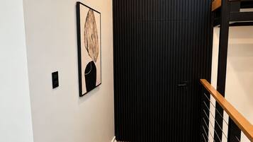 A hallway with a wooden floor, a black door, and a staircase with wooden railings.