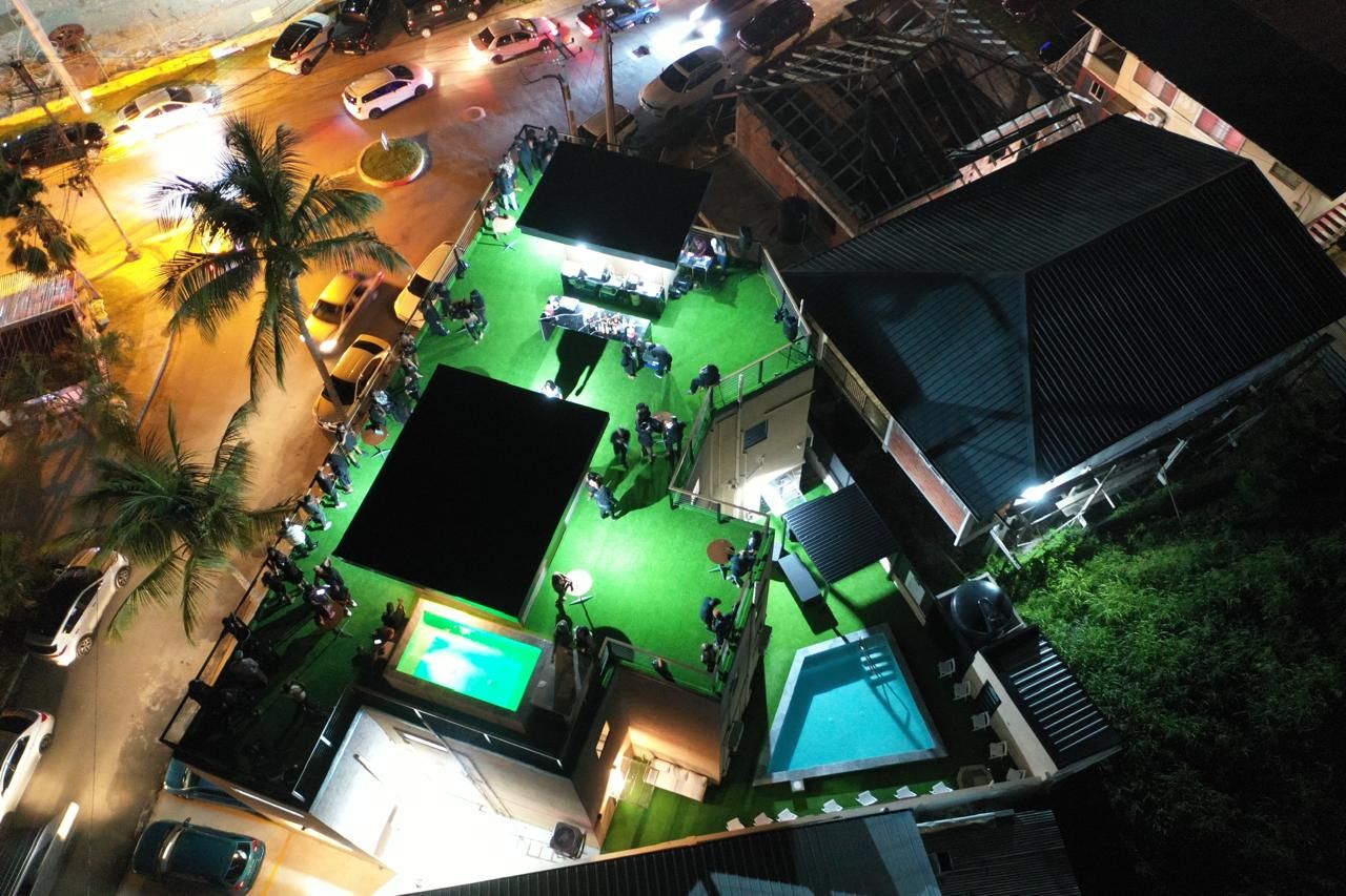 A rooftop area with a pool, a green space, and a view of the street below.