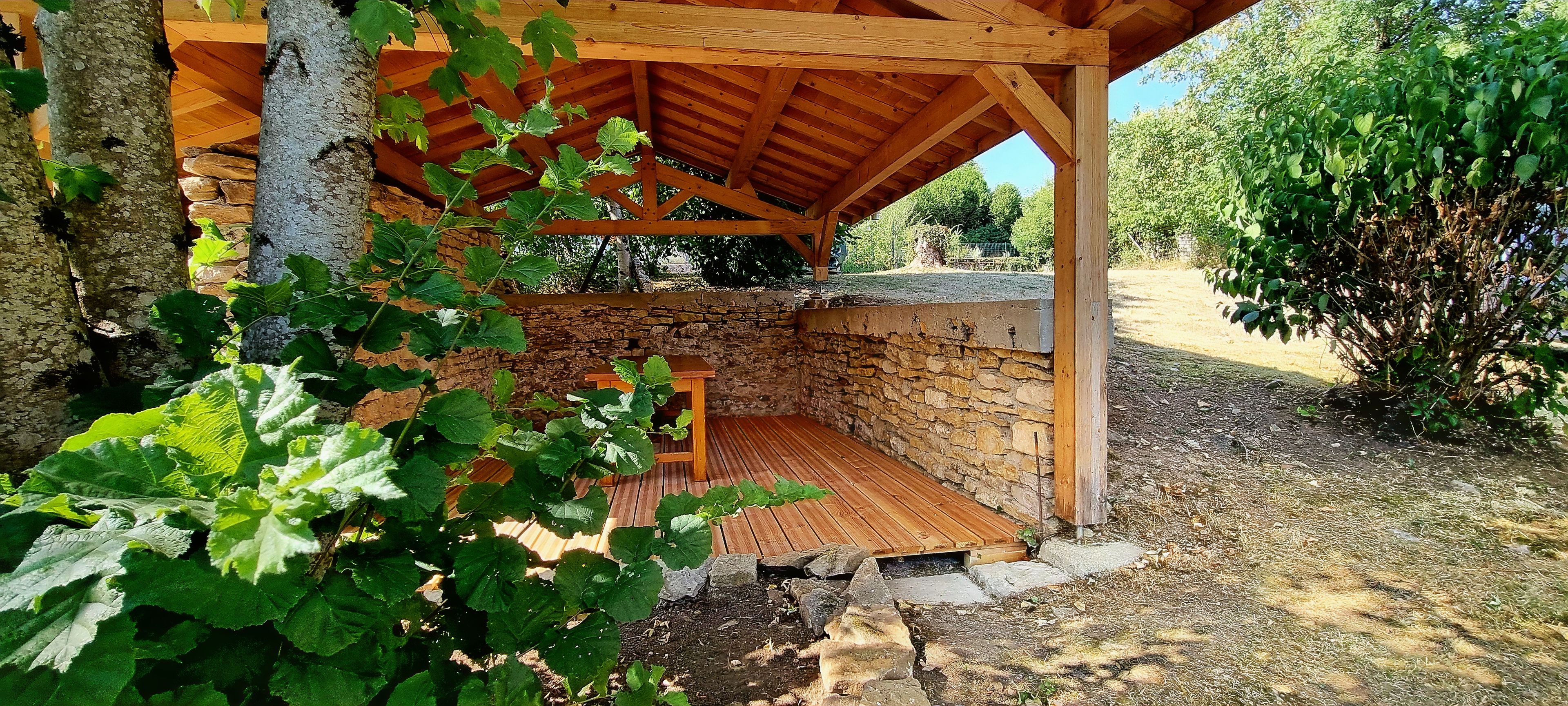 Una estructura rústica de fusta amb una paret de pedra, una cadira de fusta i una porta de fusta.