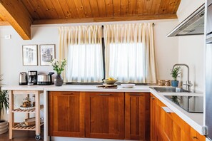 A kitchen with wooden cabinets, a stainless steel sink, a coffee maker, and a vase with flowers. - Almond Vista, Lucca Roof Garden (Lucca)