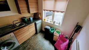 Een functionele keuken met een wasmachine, een spoelbak, een raam met uitzicht en een radiator.