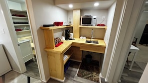 Una cocina compacta con microondas, cafetera y lavabo.