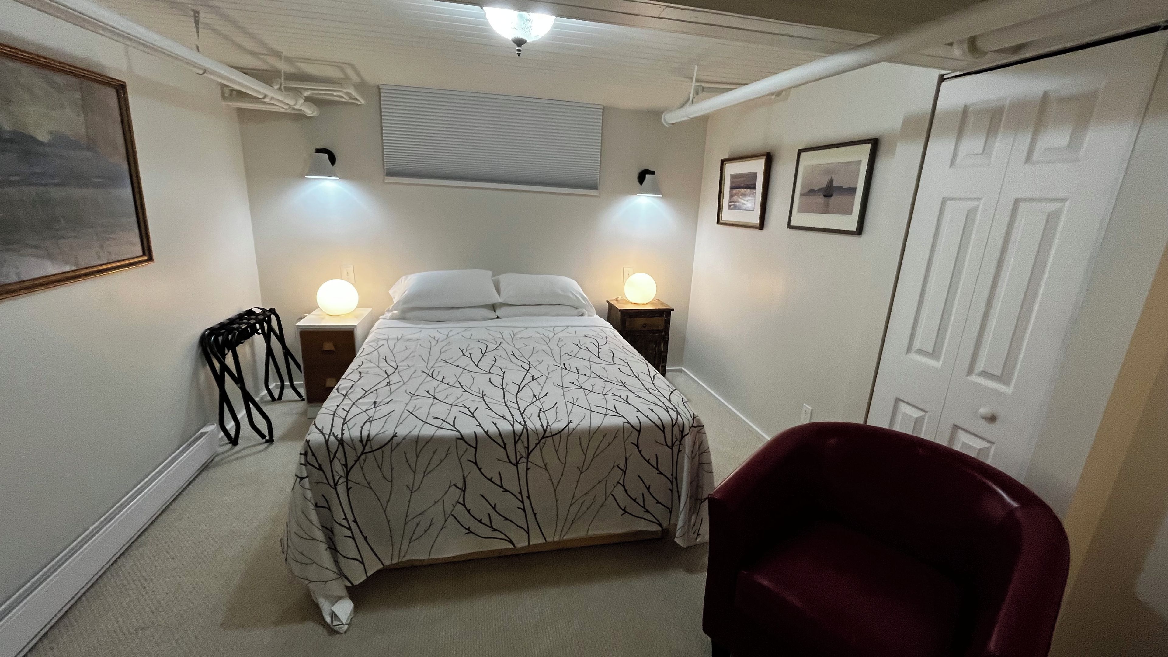 Ein Schlafzimmer mit einem Bett, zwei Nachttischlampen, einem Sessel und einer Tür.