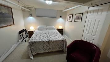 Ein Schlafzimmer mit einem Bett, zwei Nachttischlampen, einem Sessel und einer Tür.