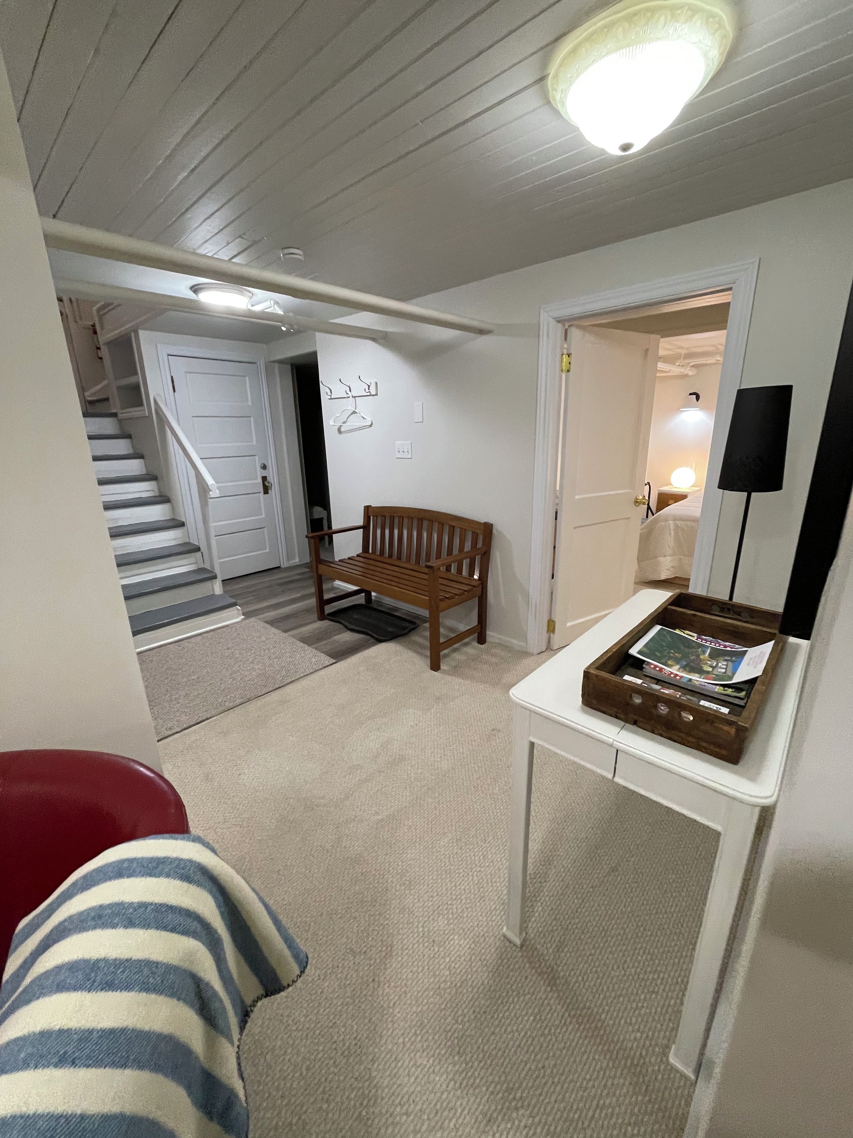 Ein Zimmer mit einer hölzernen Bank, einem Tisch mit einer Kiste, einer Treppe und einer Tür zu einem anderen Raum.